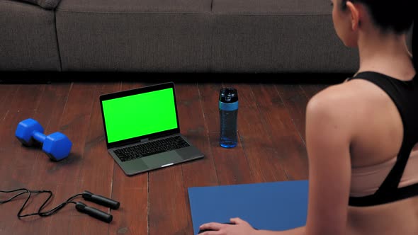 Green Screen Laptop Concept Athletic Woman in Sportswear Sits on Yoga Mat
