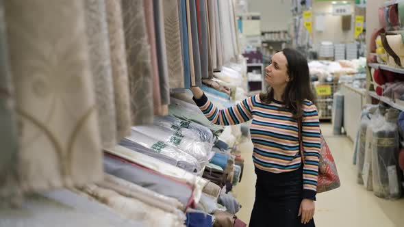 Young Woman Choosing a Curtain in Textile Shop