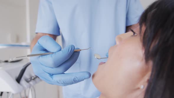 Caucasian male dentist examining teeth of female patient at modern dental clinic