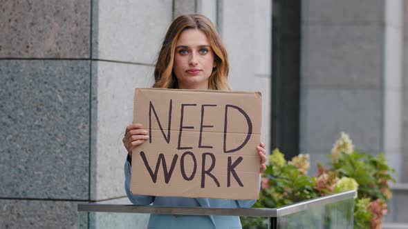 Sad Unemployed Blonde Business Woman Stands in City Looking at Camera Holds Cardboard Banner Needs