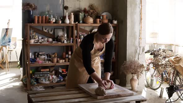 Portrait of Female Potter Wearing Beige Apron Putting Clay Piece on Worktop and Then Starting