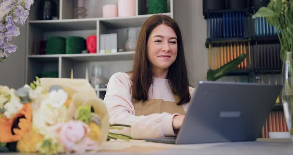 Woman Flower Shop Worker Works at a Laptop.