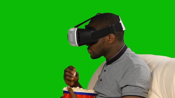 Man in a VR Mask Watching a Movie and Eating Popcorn. Green Screen