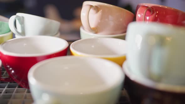 View of Colored Ceramic Mugs for Coffee Which Stand in a Special Place for Warming Up on a Coffee