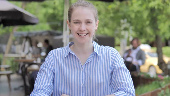 Smiling Young Woman Sitting in Cafe Terrace