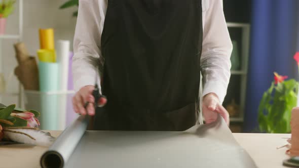 Young Florist Cutting Wrapping Paper for Bouquet at Workplace