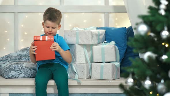 Cute Little Boy Opening Box with Gift on Christmas Day