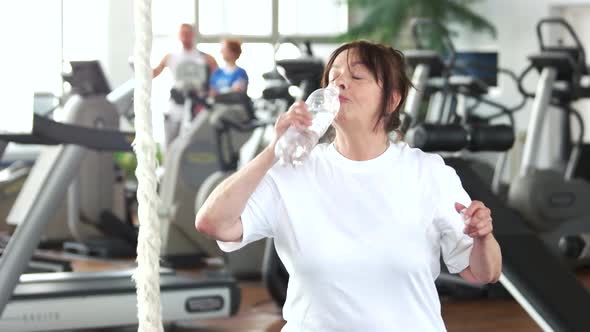 Senior Woman Drinking Water After Fitness Training.