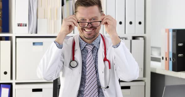 Smiling Young Medical Doctor Putting on Glasses at Workplace in Clinic  Movie