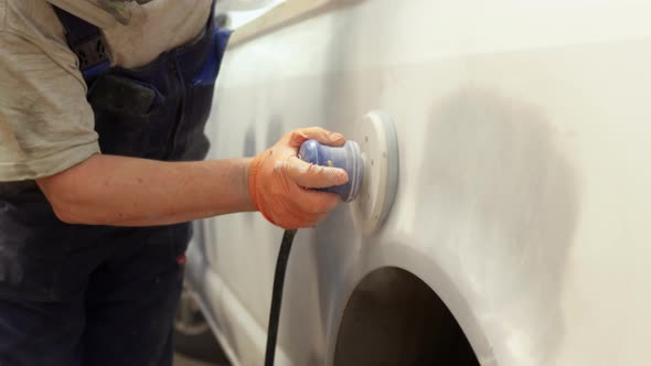 Rack Focus Mechanic in Car Service Removes Old Paint From Car and Prepares It for Painting Polishes