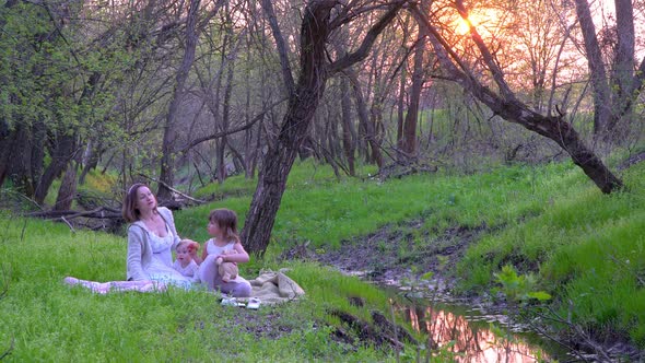 Mother and Daughters in the Forest Near the Stream