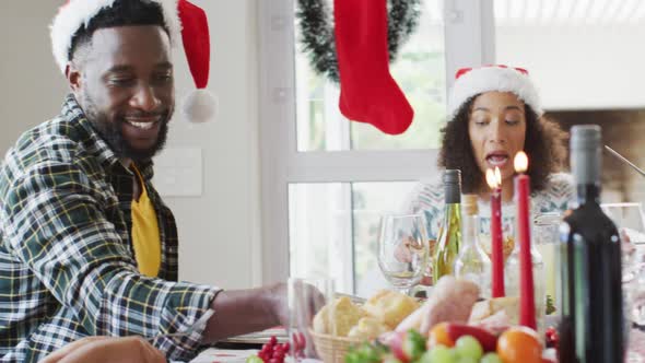 Happy african american multi generation family wearing santa hats and celebrating in kitchen