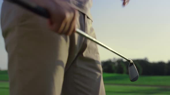 Golf Player Swinging Club Putter on Sunset Field