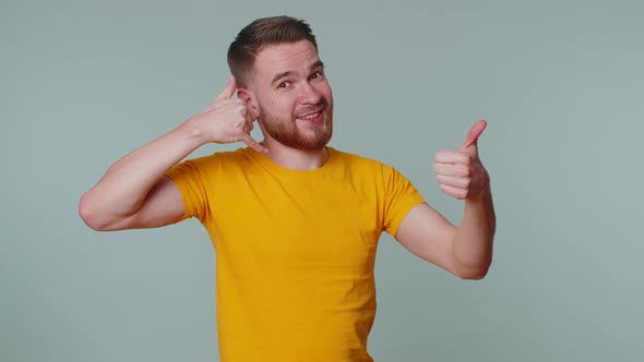 Cheerful One Man in Tshirt Looking at Camera Doing Phone Gesture Like Says Hey you Call Me Back