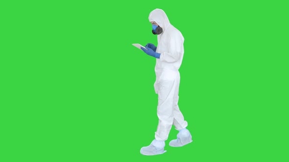 Healthcare Worker Wearing Hazmat Suit Working on Digital Tablet on a Green Screen, Chroma Key.