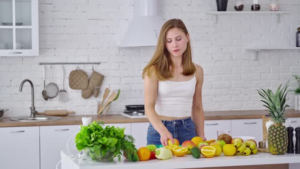 Smiling housewife at home. Sporty young woman eating healthy food in light kitchen