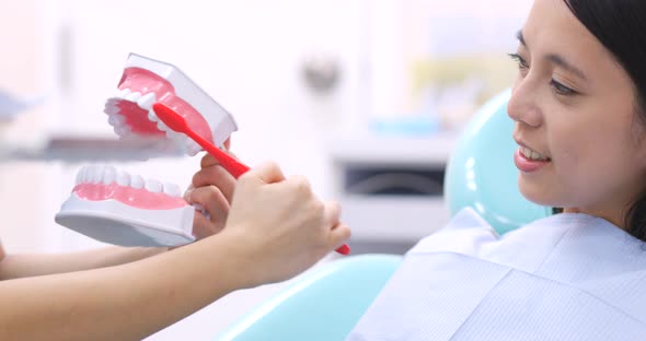 Dentist teaching patient how to brush teeth