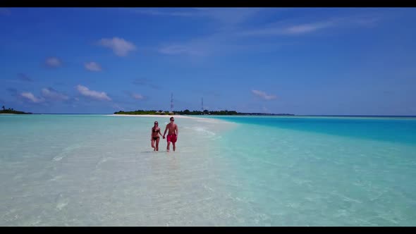 Family of two tanning on relaxing tourist beach trip by blue ocean with white sand background of the