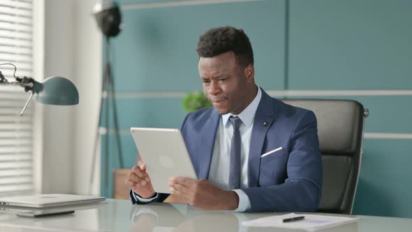 African Businessman Reacting to Loss on Tablet While Sitting in Office