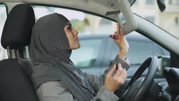 Attractive Self-Confident Muslim Lady Applying Lipstick Sitting in Car, Coquette