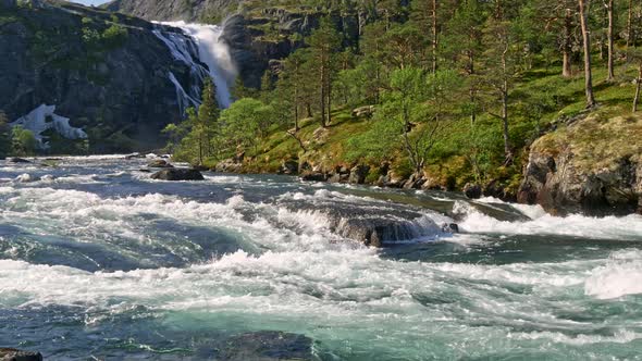 Nature of the Central Norway. Fresh Mountain River Is Flowing Fast. Waterfall in the Background. FHD