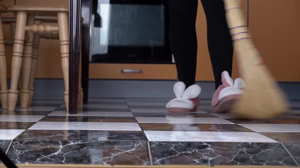 Young Girl Sweeps the Floor in the Kitchen with an Ordinary Broom