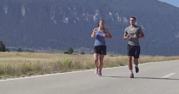 Tracking Slow Motion Shot of Sportive Couple Jogging Outdoors in the Morning Trail Running