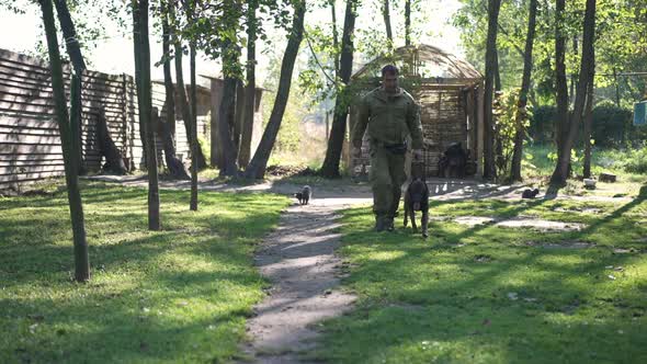 Wide Shot Man Walking Fast with Malinois Aside Outdoors on Sunny Day