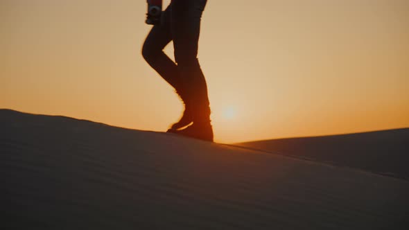 Young hiker walking on the sand at sunset, close-up
