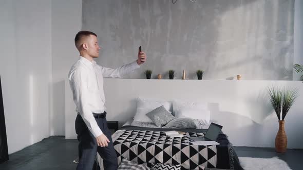 Handsome Man with Cellular in Hands Showing His Apartment