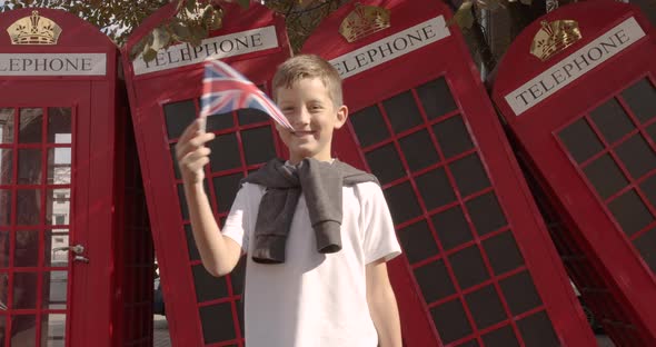 Slow Motion Portrait of Cute Boy Waving British Flag Standing Outdoors Alone Smiling Looking