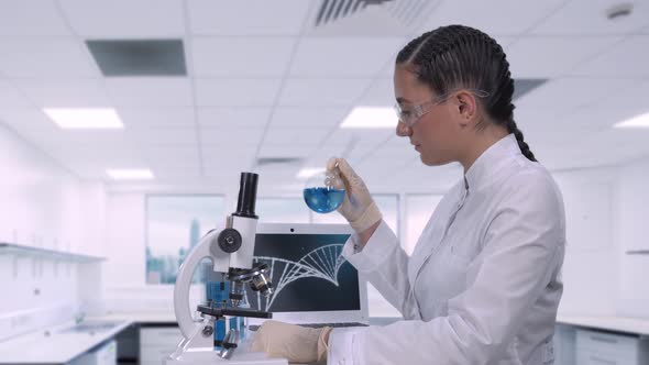 A Female Lab Technician Sitting at a Table Next To a Laptop in a Modern Medical Laboratory alt