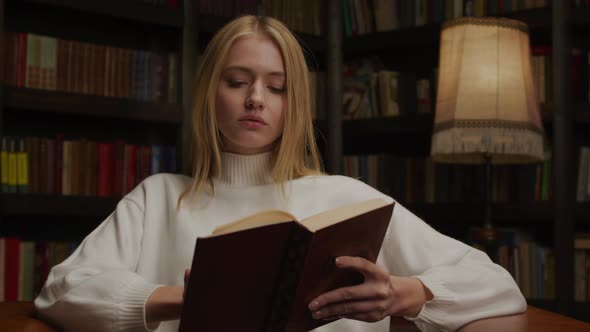 Young Adult Woman Reading a Book in an Old Library