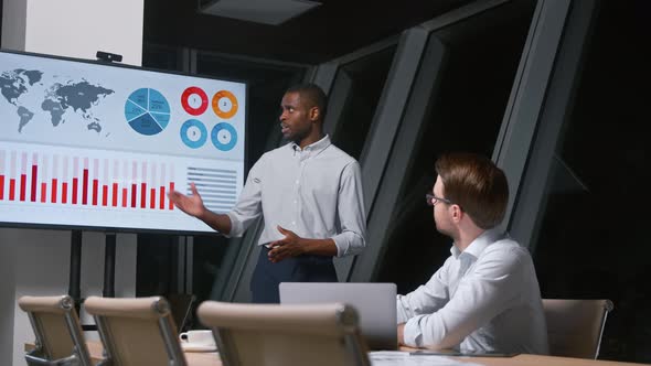 Young corporate manager telling colleague using tv multimedia