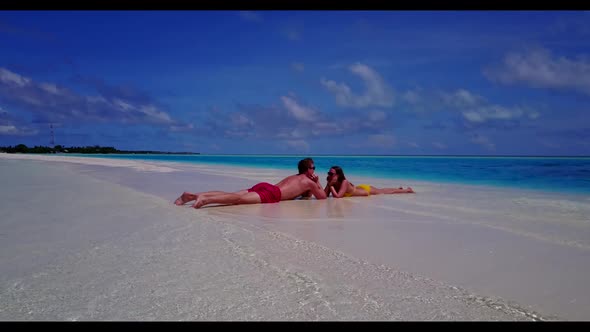 Man and woman happy together on tropical coastline beach holiday by turquoise lagoon with white sand