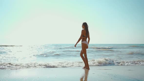 Slow Motion Footage of Happy Joyful Fitness Girl in Bikini Walks Along Sea Beach with Waves