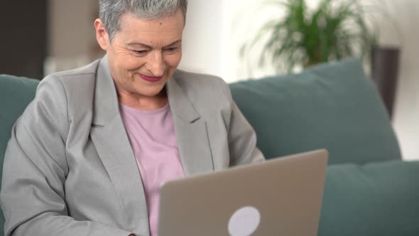 Happy Old Senior Woman Grandmother Using Laptop Computer at Home