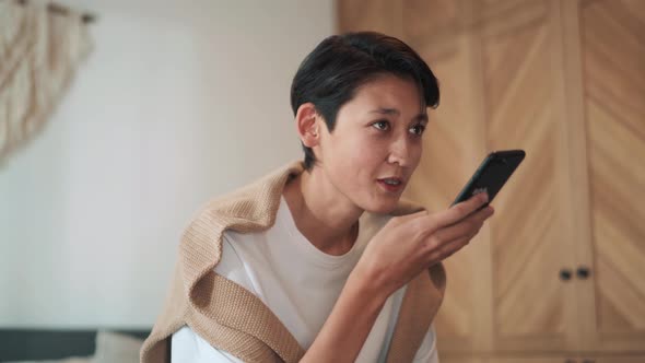 Confident Asian man recording voice message by phone