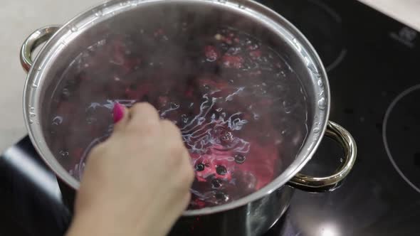 Stir the Berries in Pot with Boiling Water. Cooking Compote. Kitchen