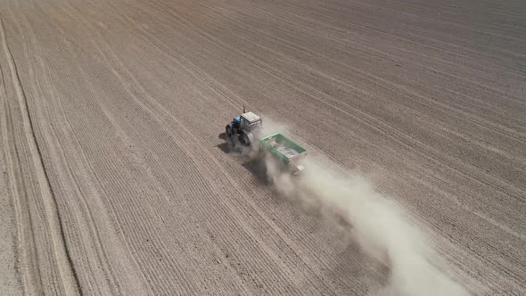 Aerial View  Video of Tractor with Fertilizer Trailer Fertilizes the Field After Planting