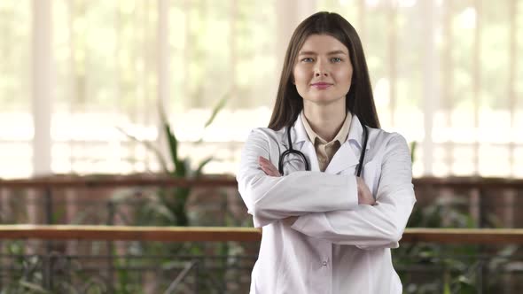 Portrait of a Confident Young Female Doctor Happy with Her Work in the Hospital Corridor