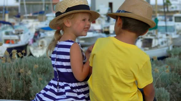 Back View of the Adorable Little Boy and Girl in Straw Hats Laughing Together