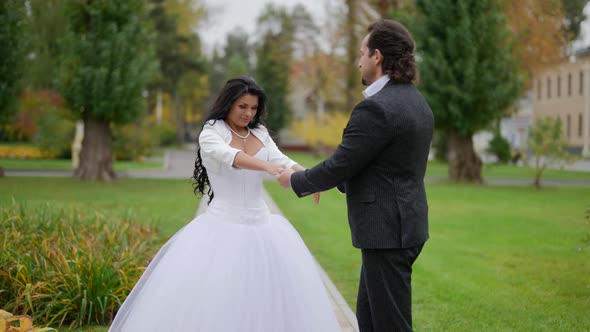 Beautiful Bride is Holding Her Groom Hand and Walking with Him on Street