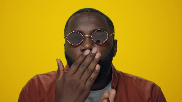 Portrait of Handsome Afro Man Sending Air Kiss to Camera on Yellow Background