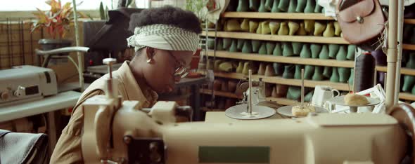 Black Woman Cutting Leather at Desk in Shoemaker Workshop