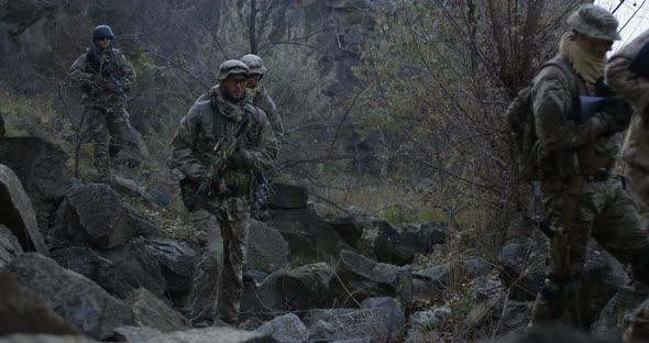 Armed Soldiers Walking Through Rocks at Dusk alt