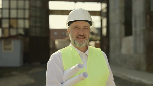 Chief Engineer Holding Work Blueprints at Building Object