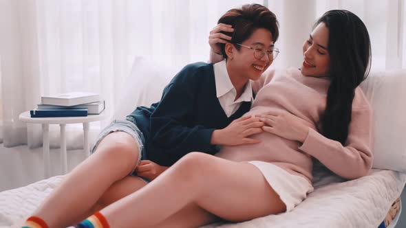 Pregnant Asian lesbian woman and her partner are happy to spend time together at home.