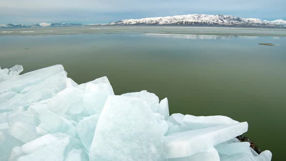 Time lapse looking past ice blocks as sheet of ice floats by in Utah Lake