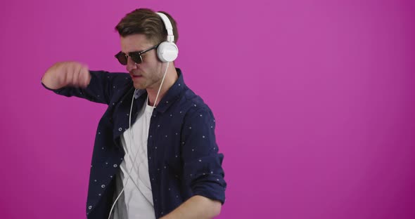 Man Dancing and Smiling Over Color Background While Listening to Music